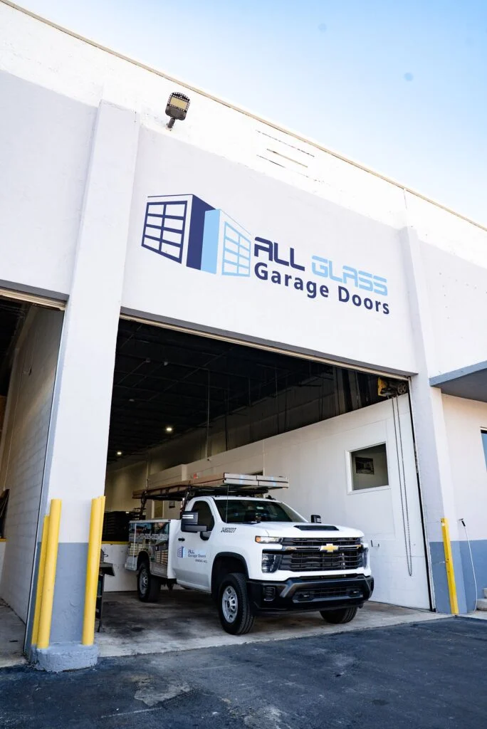 All Glass Garage Doors factory building in Doral, Florida, with a service truck at the loading door