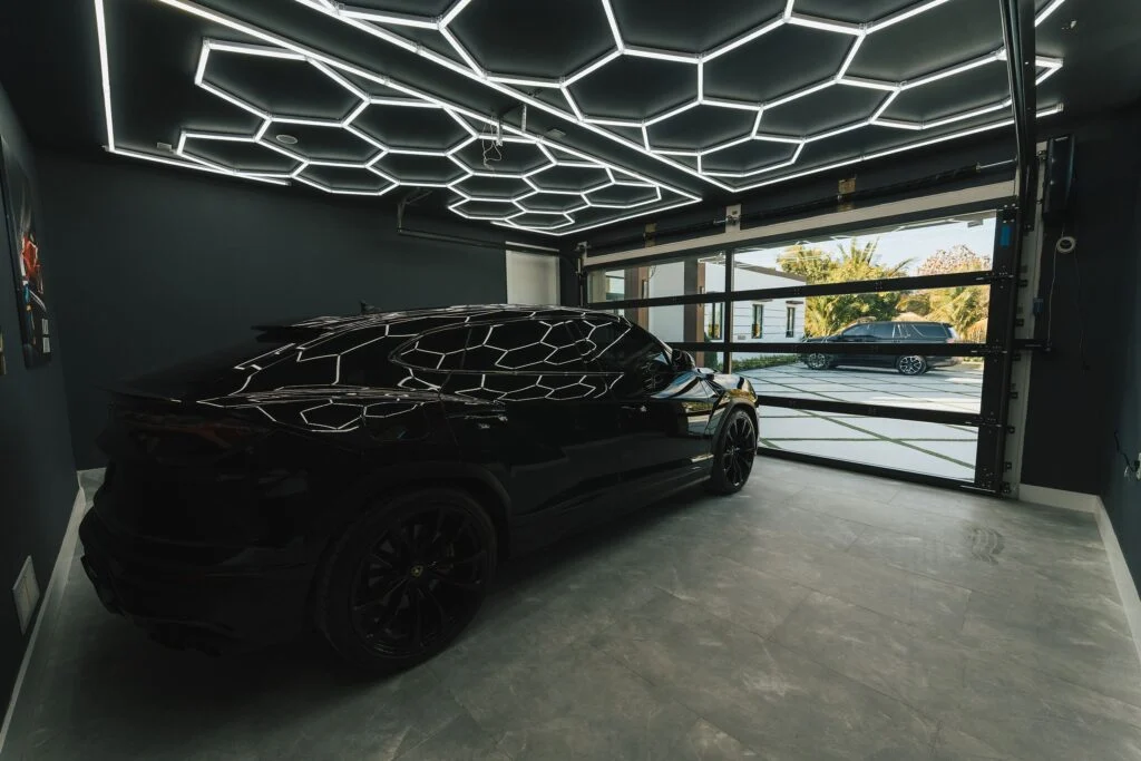 Car inside a garage behind a Dubai Framed glass door with hexagon ceiling lights