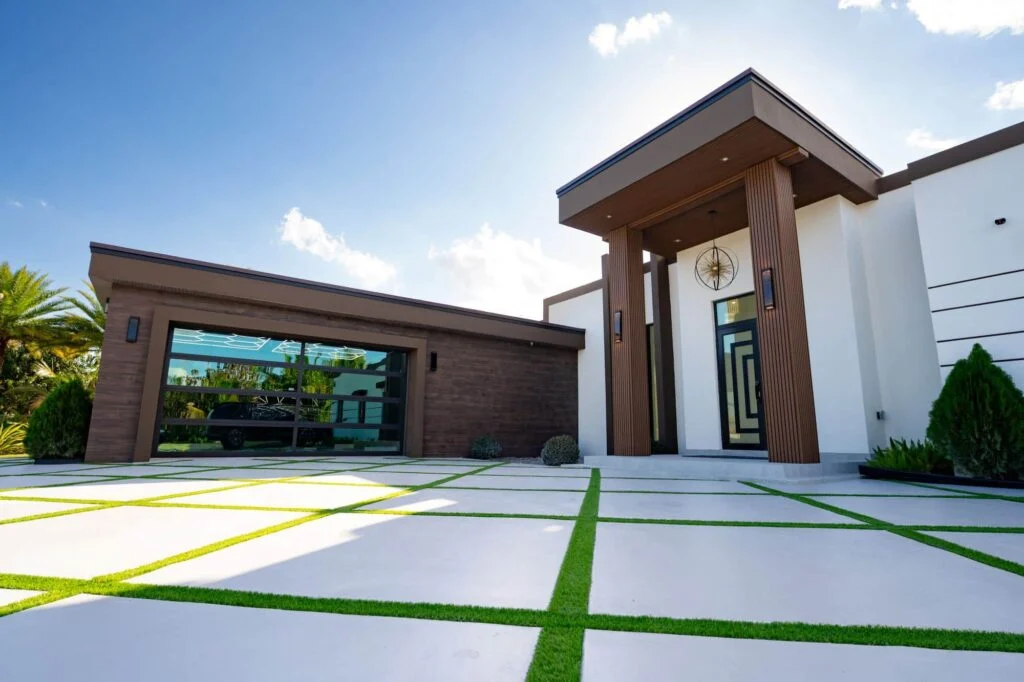 Modern home with a wood-clad two-car Dubai Framed glass garage door and grass-strip driveway