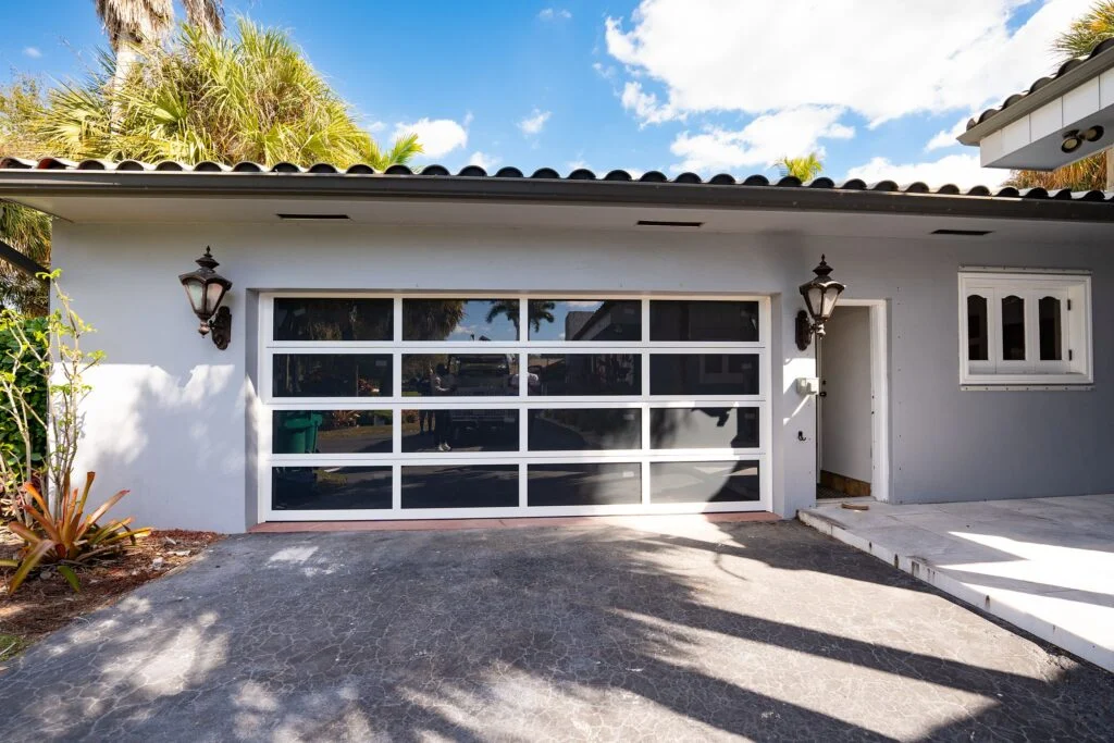 Two-car Dubai Framed garage door with white frames and dark glass on a white Mediterranean-style home