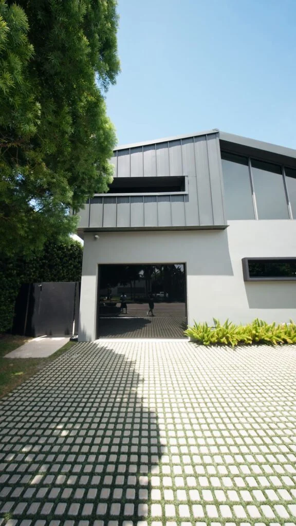 Modern home with a Dubai Frameless black glass garage door and grass-paver driveway