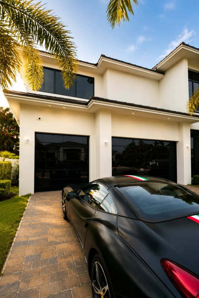 Black mirror Dubai Frameless garage door with a car on a paver driveway