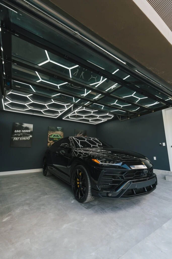 Garage with hexagon ceiling lighting and a black SUV behind a glass garage door