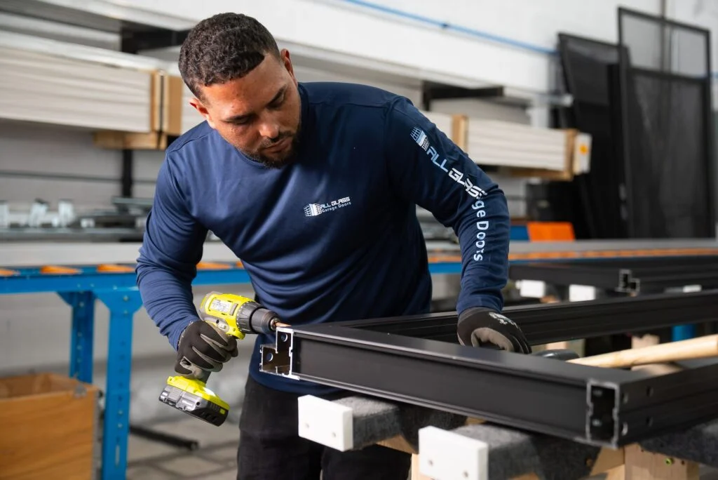 All Glass technician assembling a black aluminum door section frame in the Doral factory